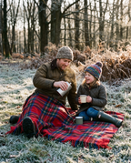 Father and daughter on the Royal Stewart tartan wool blanket on frosty grass