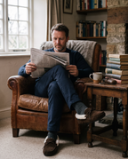 Man reading in an armchair wearing the brown suede sheepskin moccasin slippers