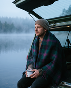 Man by a misty lake with the Baird tartan wool blanket around his shoulders